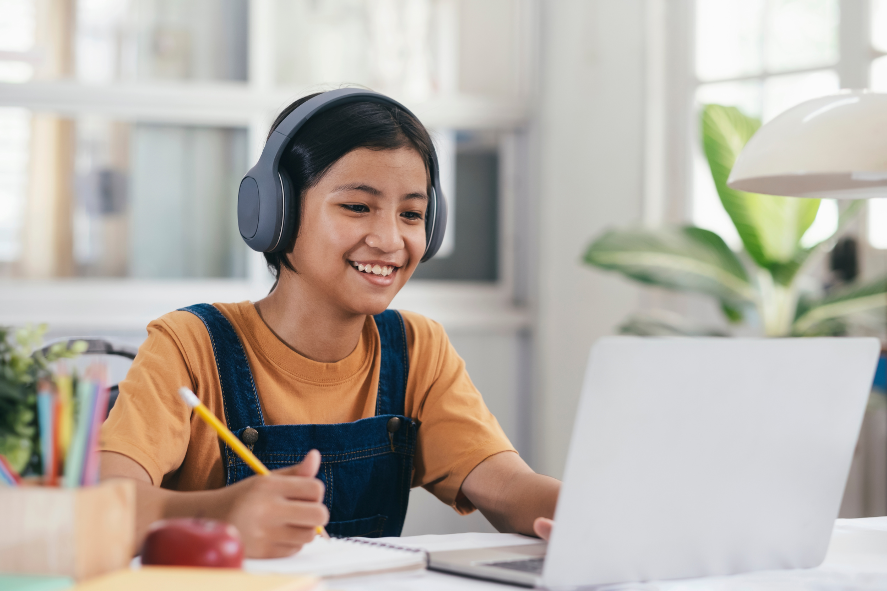 child at desk with headphones and laptop